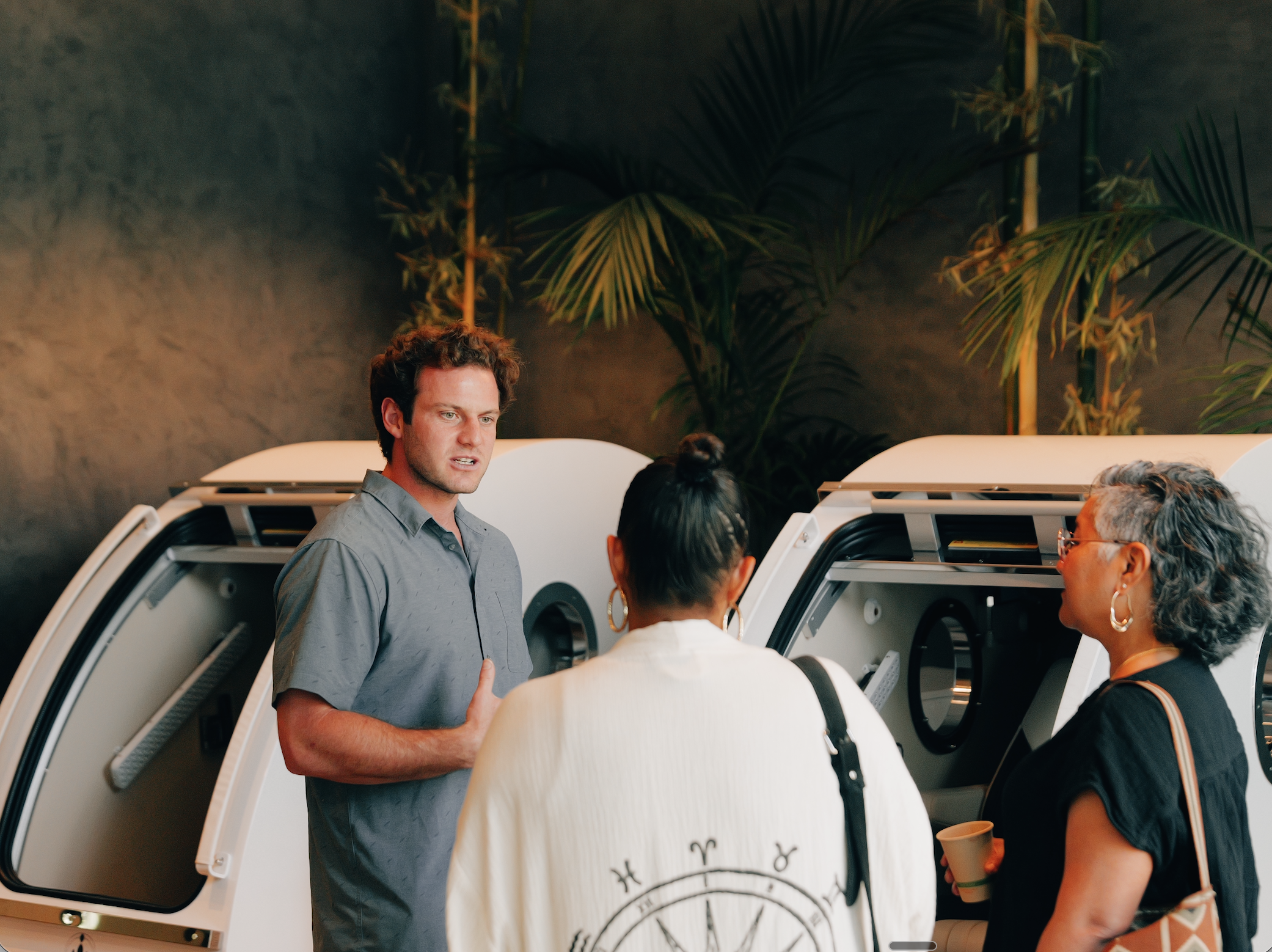 A Citrin Longevity team member explaining the hyperbaric oxygen pods to two clients at the West Hollywood clinic