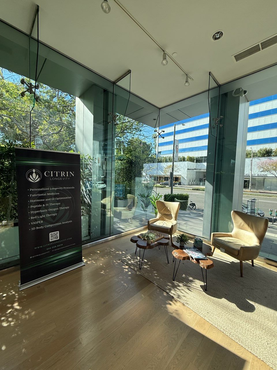 The sunlit Citrin Longevity reception and lounge in West Hollywood, with floor-to-ceiling windows and the clinic's service banner